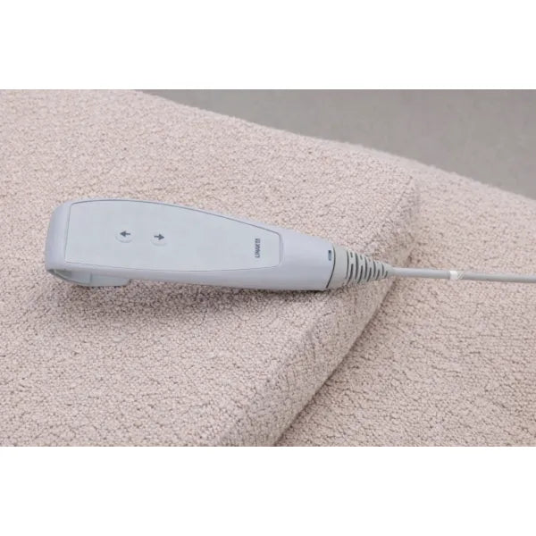 Fernbedienung der FLAT ELEMENT Elektrische Massageliege auf hellbeigem Handtuch.