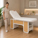 INDUS spa bed with hydraulic backrest and storage shelves, white with oak panels, in a professional treatment room.