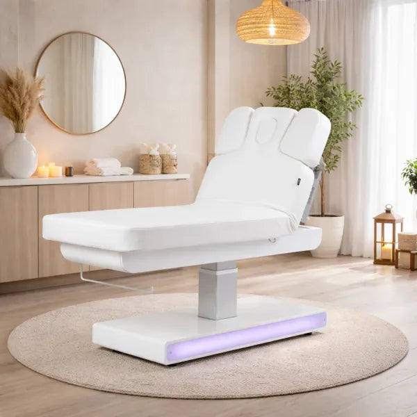 Weiße elektrische Massageliege mit drei Motoren NUSH+ in modernem Spa-Setting, LED-Beleuchtung am Sockel.