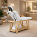 Holz-Massageliege mit weiße 2-Zonen-Auflage, Kopfteil & unterem Handtuchablage für Spa & Kosmetikstudio.