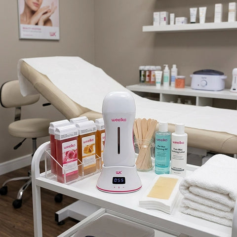 Cordless wax heater for professional waxing: ONEWAX Profi Wax Device on salon cart with wax bottles.
