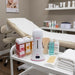 Cordless wax heater for professional waxing: ONEWAX Profi Wax Device on salon cart with wax bottles.