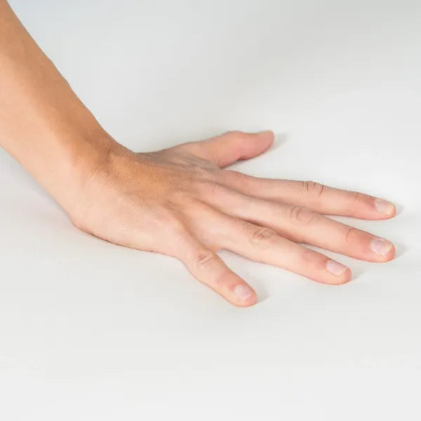 Eine Hand ruht flach auf einer weißen, glatten Oberfläche – Wellness-Umgebung.