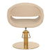 Moderner Friseurstuhl in Beige mit ovaler Sitzschale, goldfarbener Hydraulik und runder Grundplatte für stilvolle Salons.