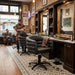 Schwarzer hydraulischer Friseurstuhl mit Armlehnen in einem barbierischen Salon mit goldenen Spiegeln und Backsteinwänden.