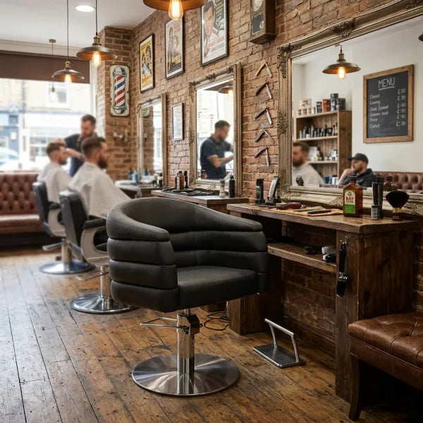 Schwarzer hydropultilbarer Friseurstuhl mit Armlehnen und Polsterung in einem Barbershop mit Holzboden.