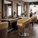 Hydraulischer Friseurstuhl mit Armlehnen und quiltetem Polster im modernen Barbershop mit Marmortisch und Backsteinwand.