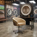 Beige Friseurstuhl mit Armlehnen und Chromgestell in einem-Barbershop mit runden LED-Spiegeln und Industriestil.