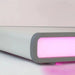 Weiße elektrische Massageliege mit LED-Beleuchtung in pinkem Licht, modernes Spa-Design