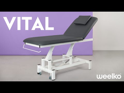 Therapist performs back massage on client on a height-adjustable electric massage bed in a spa setting.