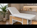 INDUS spa cosmetic bed with hydraulic backrest, white upholstery, oak panels and storage shelves.