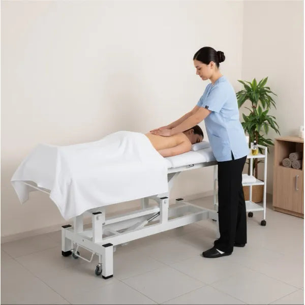 Therapist performs back massage on client on a height-adjustable electric massage bed in a spa setting.